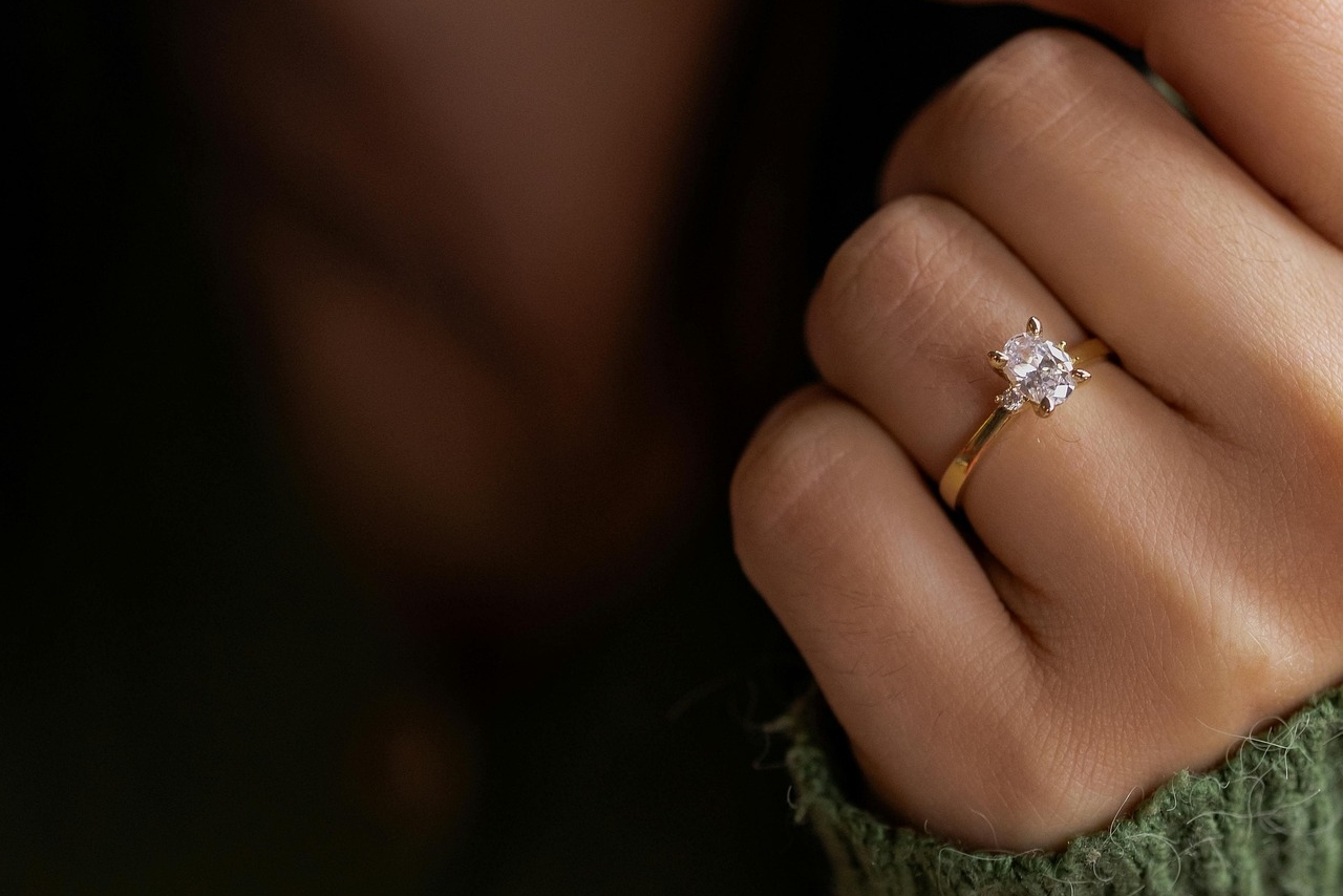 A close-up of a woman’s hand adorned with a yellow gold solitaire engagement ring.