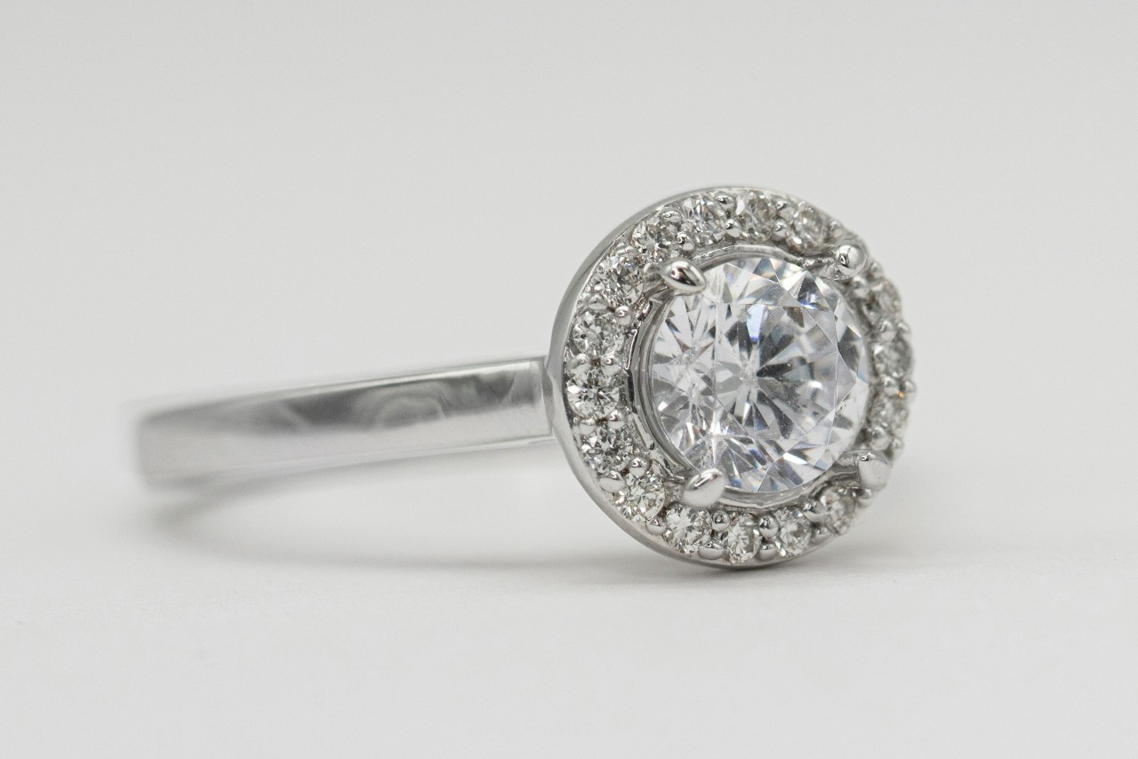 a silver toned engagement ring with a round cut center stone and halo setting