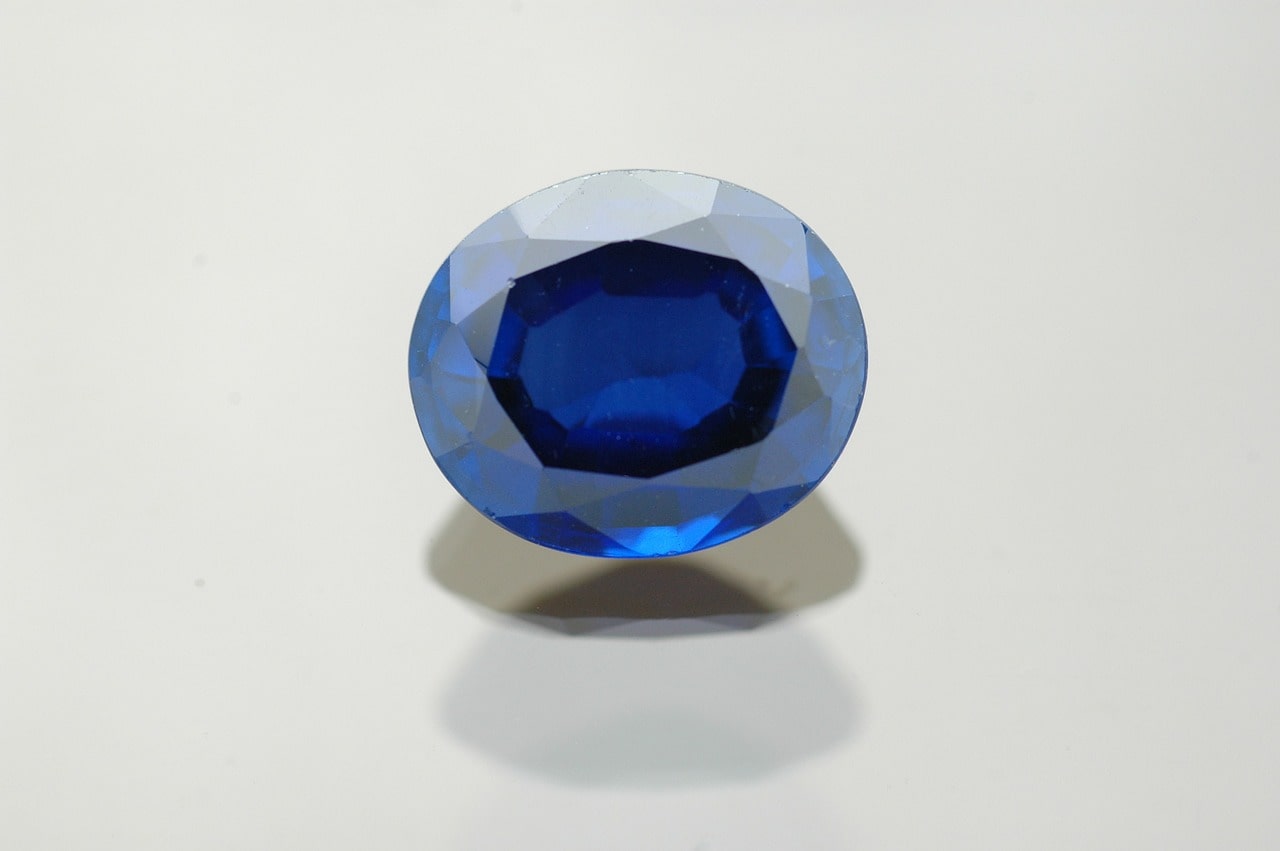 A close-up of a sapphire stone on a plain white surface.