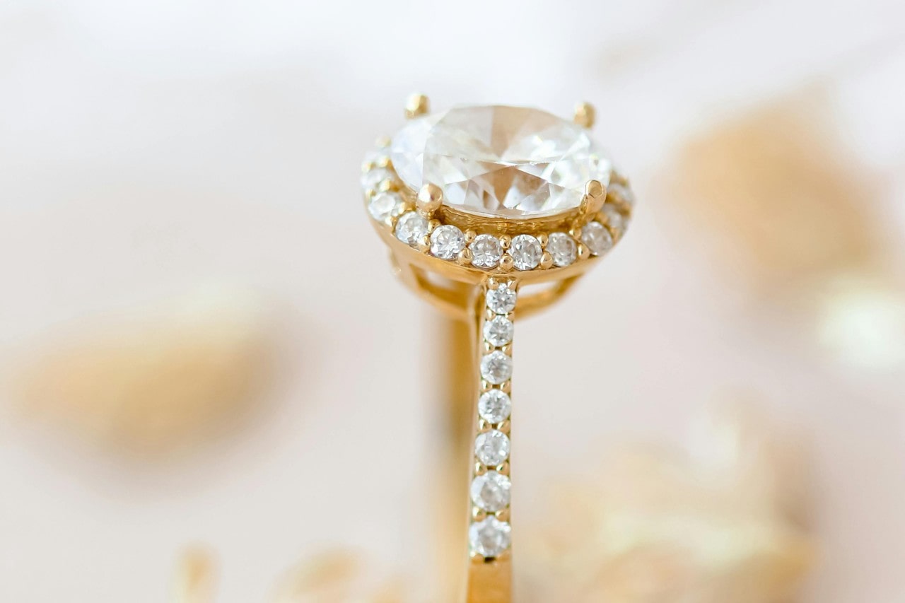 close up image of a yellow gold engagement ring with an oval cut diamond