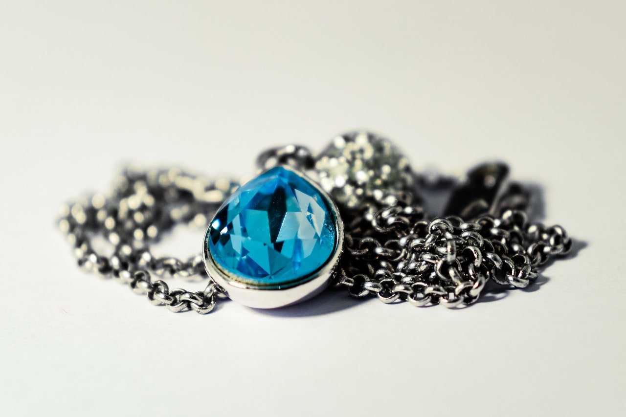 A saturated close-up photo of a Yogo sapphire pendant necklace on a white gold chain.