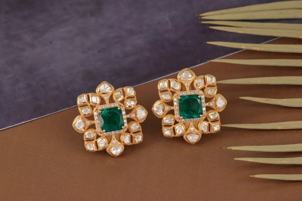 Two yellow gold flower shaped halo earrings with square emeralds as the center stone