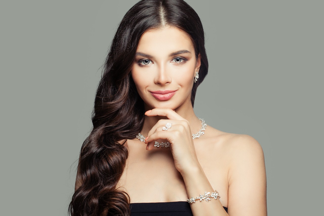 A woman in a strapless black top showcases a full set of matching floral diamond jewelry including earrings, necklace, bracelet, and ring.