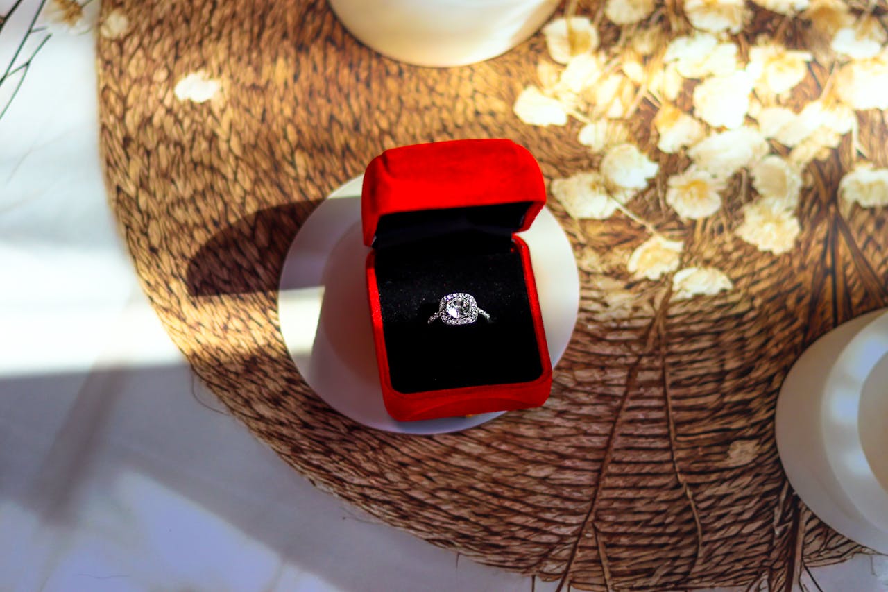 A white gold side-stone engagement ring inside a velvet box on top of a coaster.