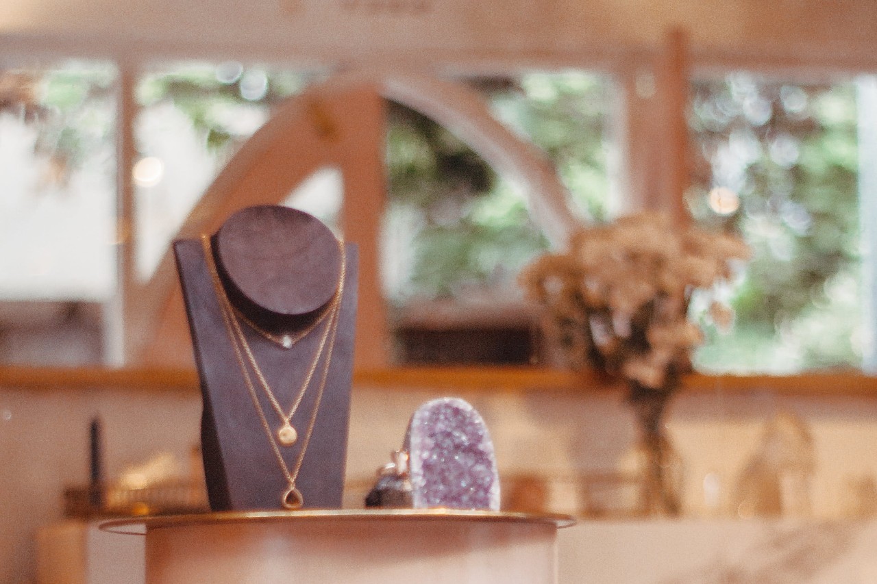a necklace stand next to a purple crystal on a table in a jewelry store a necklace stand next to a purple crystal on a table in a jewelry store
