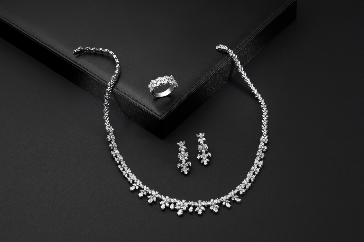 Elegant diamond necklace set with matching earrings and ring against a black background. Elegant diamond necklace set with matching earrings and ring against a black background.