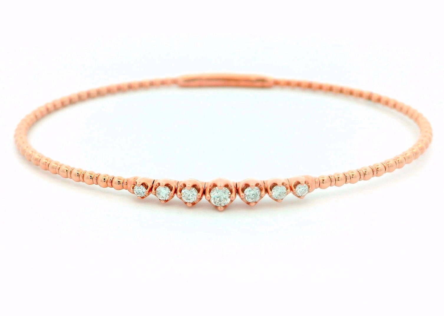 A rose gold beaded oval bagel on a white background