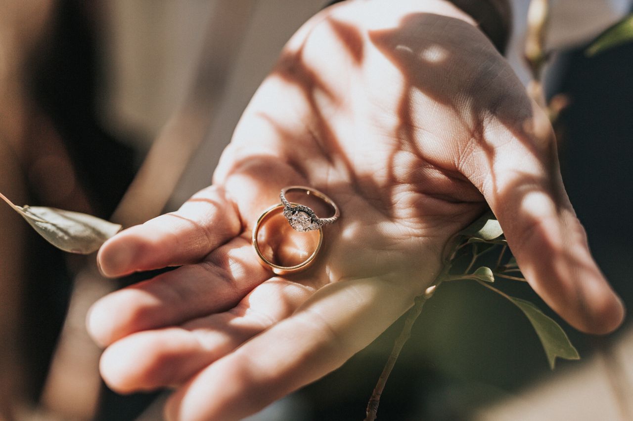 A diamond three stones engagement ring with gold wedding band on the palm A diamond three stones engagement ring with gold wedding band on the palm