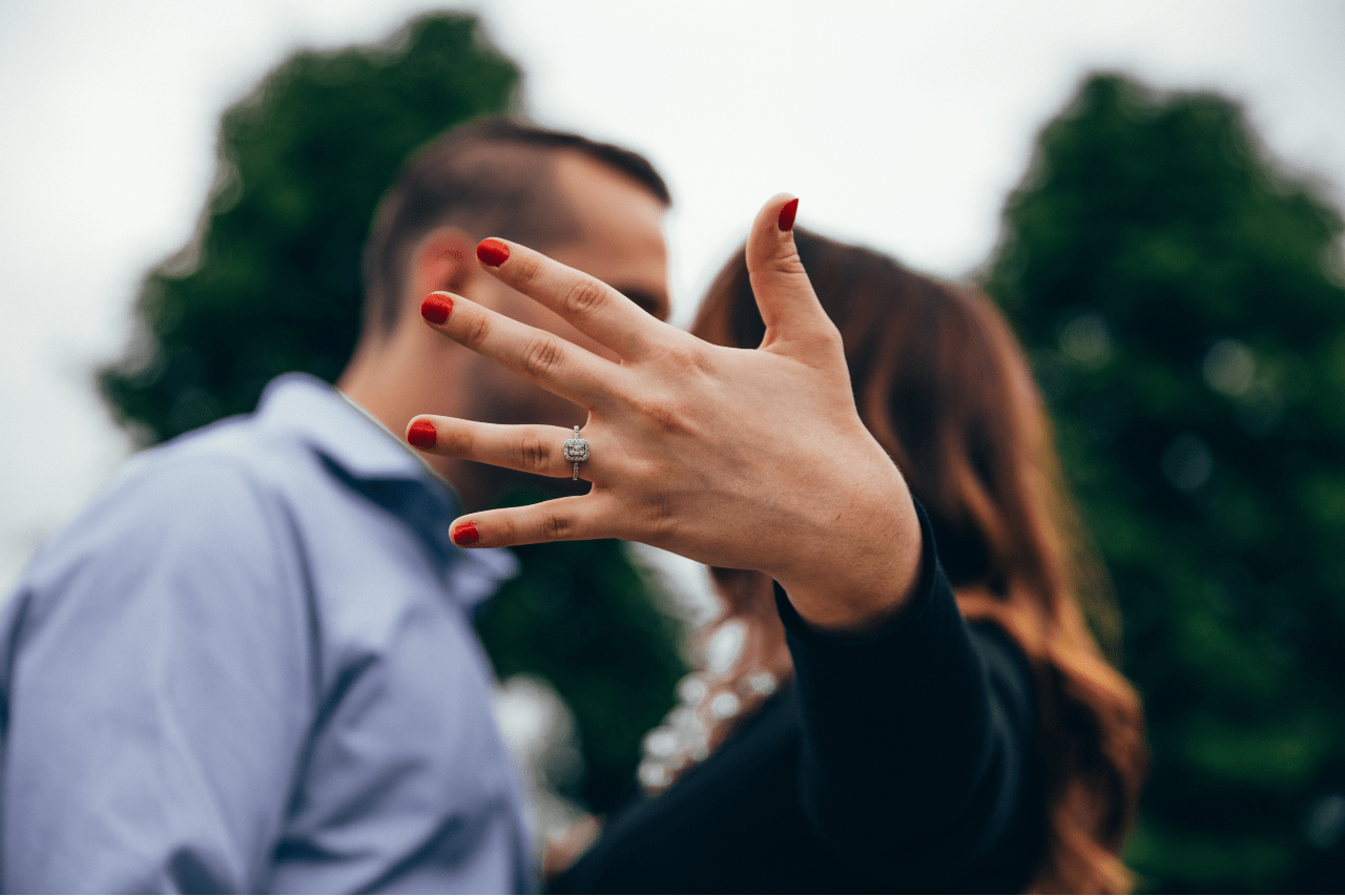 A woman showcasing her diamond engagement ring while kissing her fiance A woman showcasing her diamond engagement ring while kissing her fiance